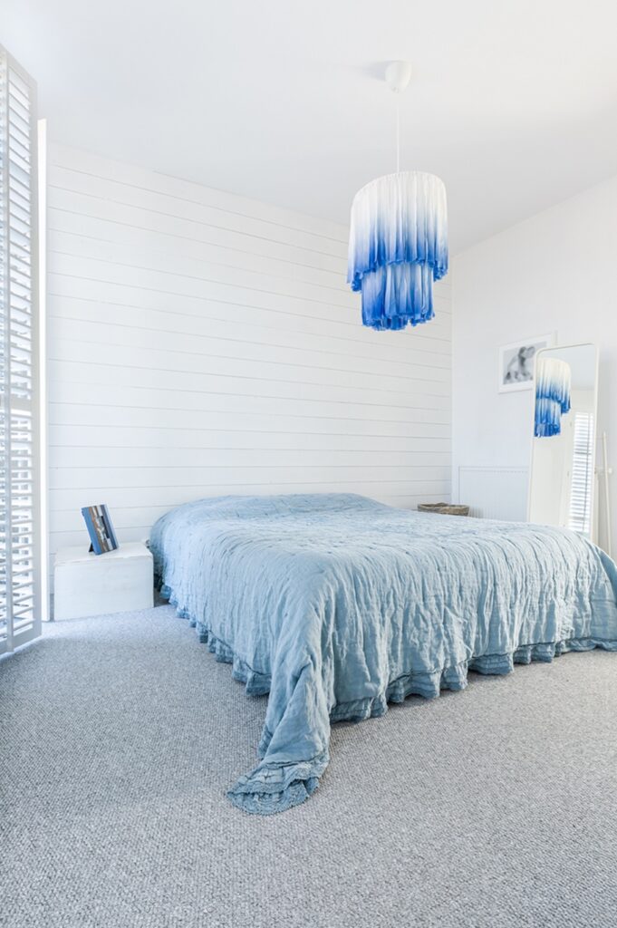 Stylish modern white and blue chandelier in trendy spacious bedroom with king size bed